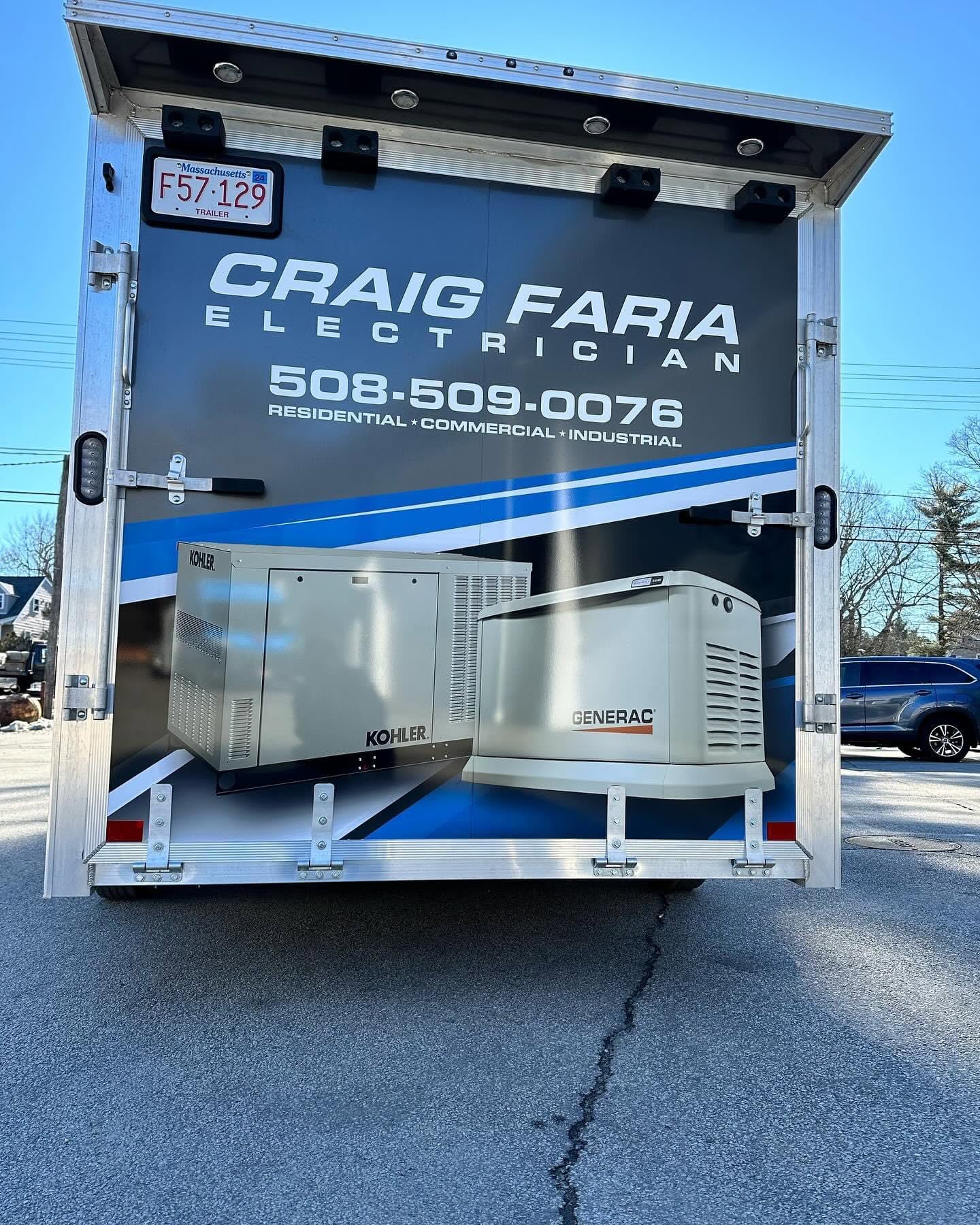 Rear of an electrician’s truck displaying company name, contact info, and images of Kohler and Generac generators parked on a paved surface.